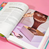 The Crumbs & Doilies Recipe Book open to a chocolate brownie recipe with a photo of rich brownie batter being poured.